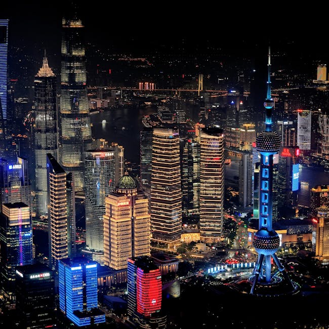 A stunning aerial view of Shanghai's cityscape at night featuring the illuminated Oriental Pearl Tower.